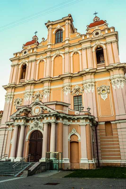 What to see in Vilnius: View of the pink facade of St. Casimir's Church, the first Baroque church in Vilnius and one of the must-see attractions on this free self-guided Vilnius walking tour.