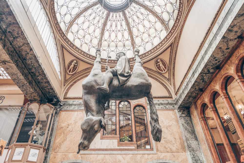 Free Prague walking tour: View of the King Wenceslas Riding on a Dead Horse, one of the best sculptures to see in Prague by David Cerny. It shows a  a saint sitting atop an upside-down, dead horse and is a mocking reference to the equestrian statue of Saint Wenceslas. PC: tichr/shutterstock.com