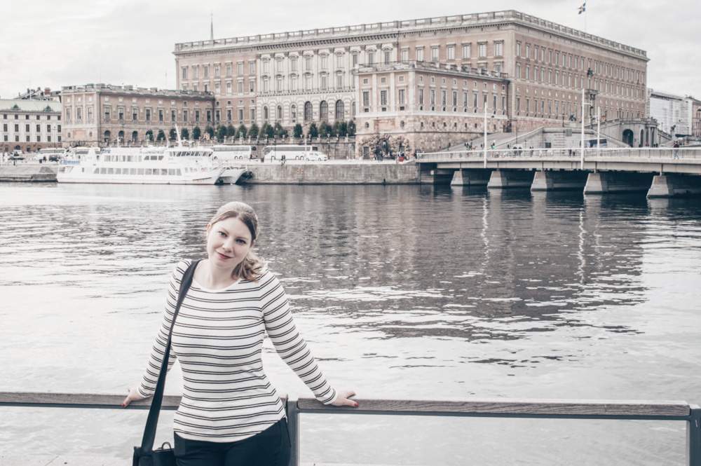 Stockholm sightseeing: Beautiful woman standing by the canal with the Royal Palace in the background
