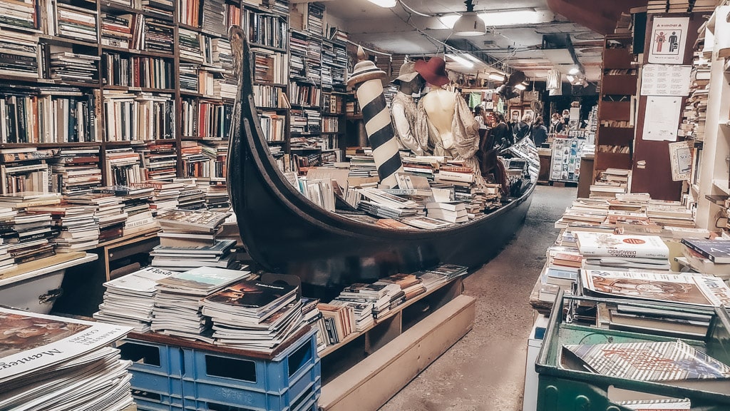 Piles of books stacked in shelves and in a full-sized gondola at the Acqua Alta Bookstore (Libreria Acqua Alta) in Venice.