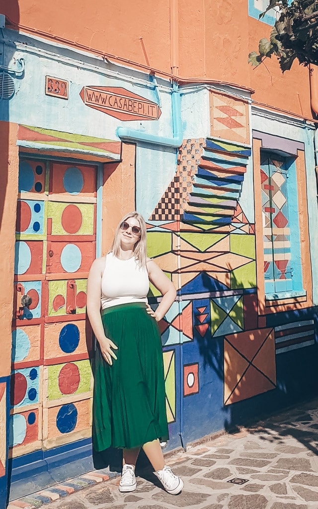 Beautiful blonde woman standing outside the dazzling Casa Bepi in Burano, Italy.