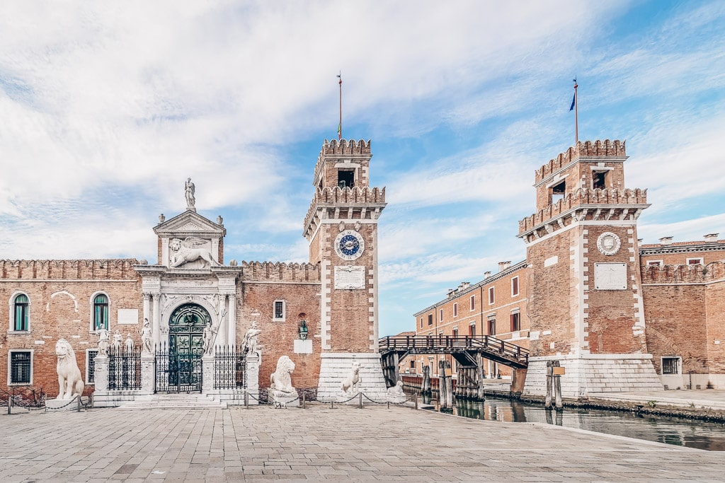 The impressive arched Renaissance gateway of the Arsenale of Venice guarded by four white stone lions.