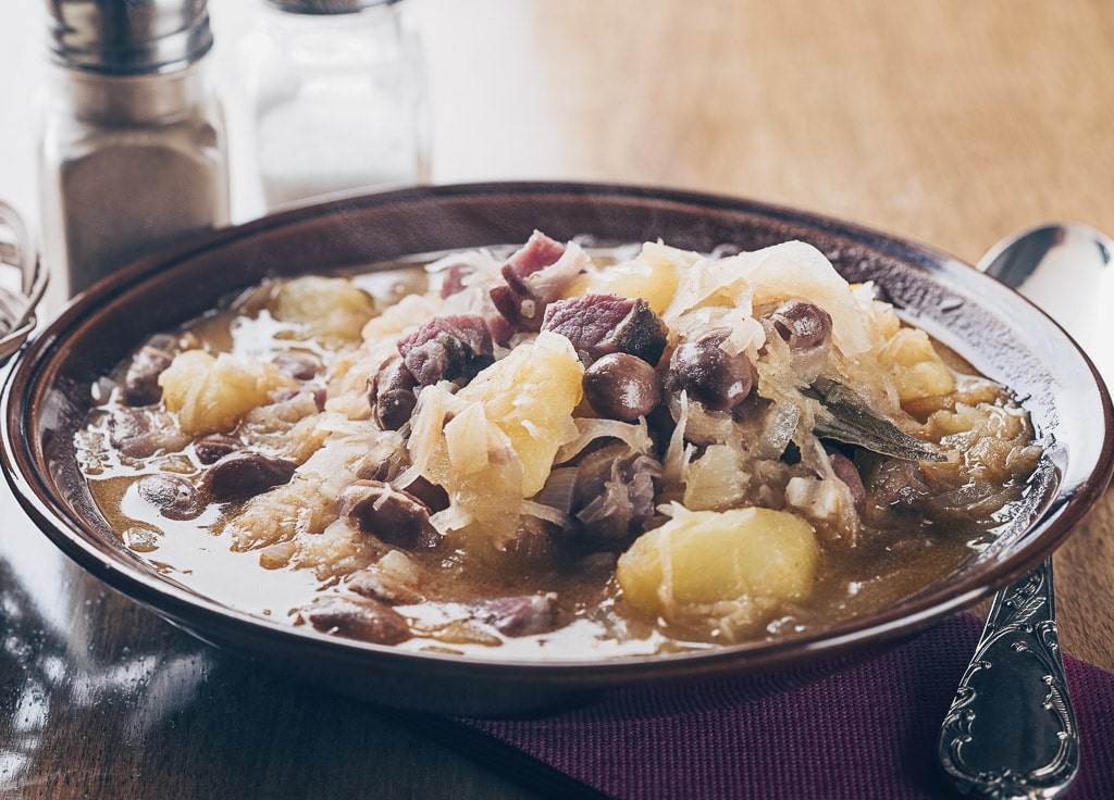 Hearty jota stew made with beans, potatoes, sauerkraut, and smoked Carniolan sausage.