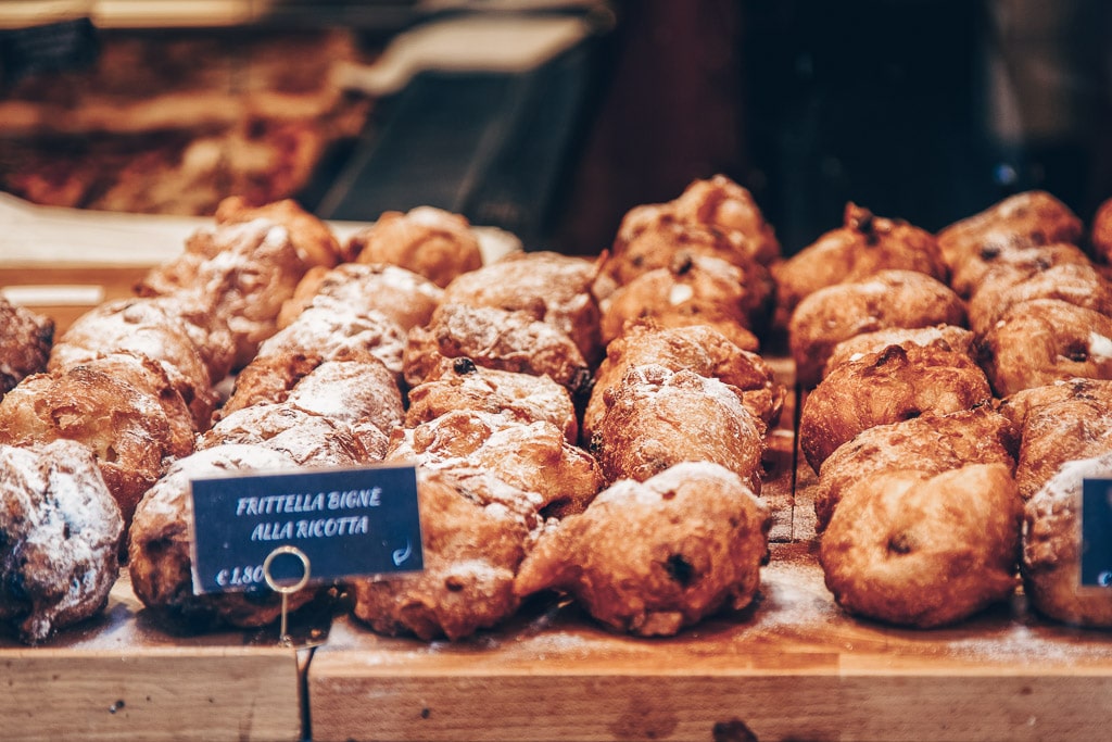 Venice Carnival: A counter of traditional frìtole, dough ball fritters laced with liquor-soaked raisins, pine nuts, and dusted with sugar.