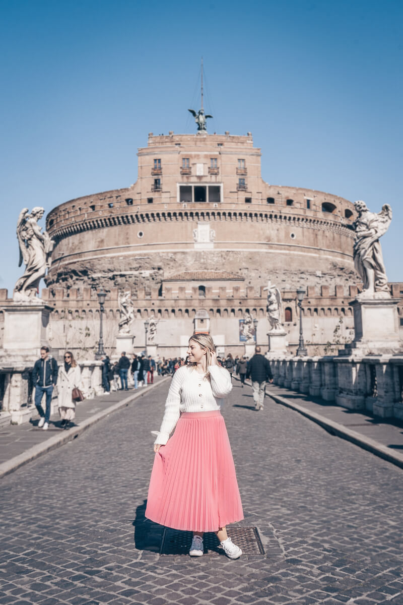 Rome must-see: Woman posing for a photo in front of the imposing Castel Sant' Angelo on a sunny day