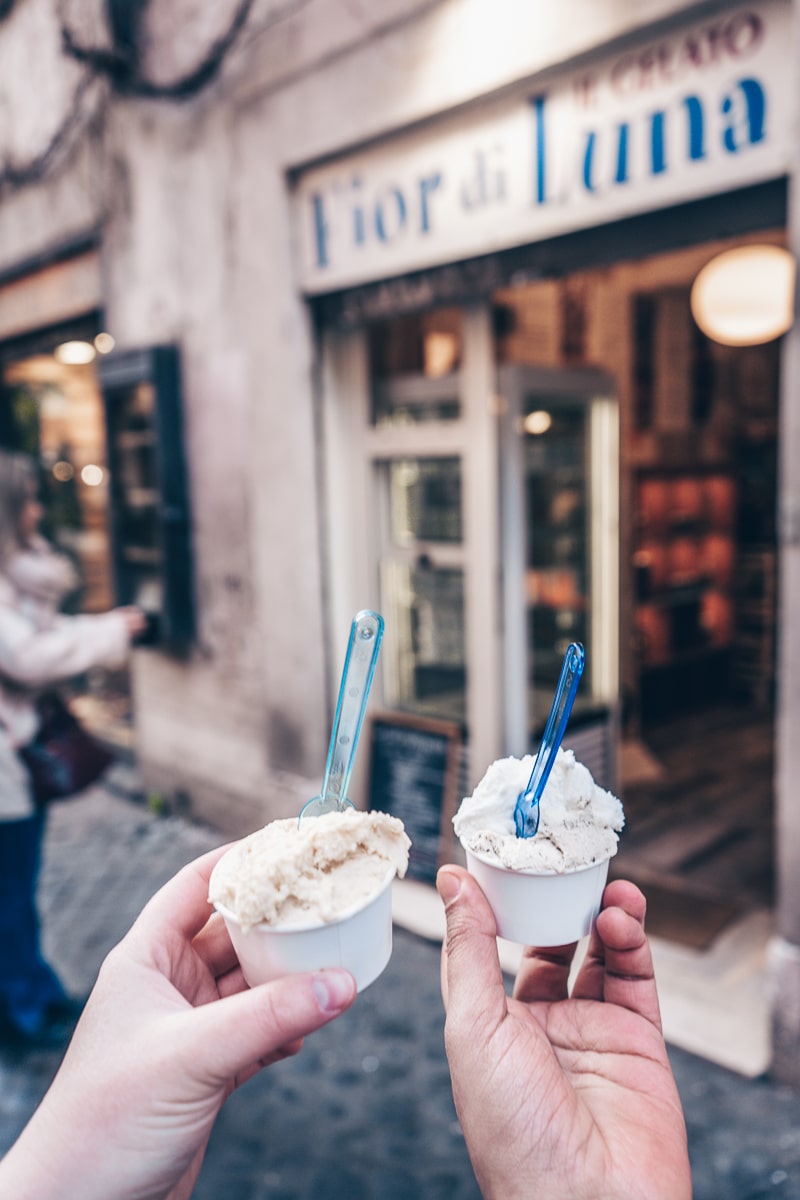 Best gelato in Rome - A couple holding two cups of gelato in front of Fiordiluna gelateria in Trastevere