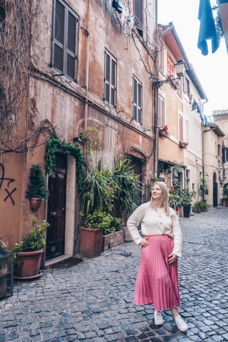 Rome photo spots: A beautiful blonde woman posing for a photo in a cobbled alley in Trastevere
